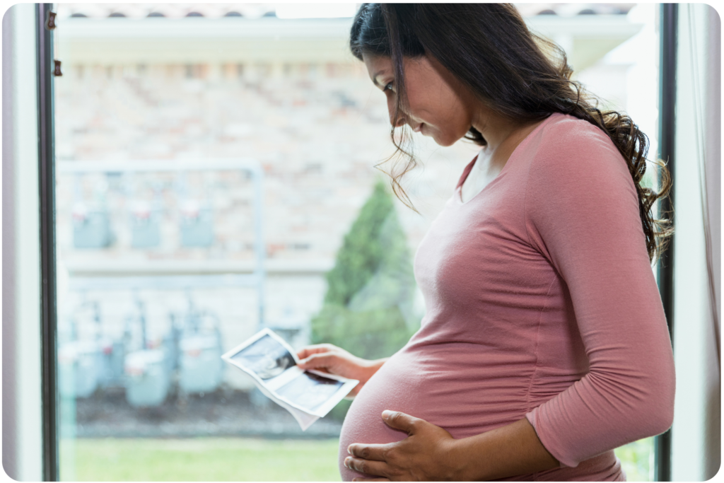 Pregnant woman in pink shirt viewing an ultrasound picture