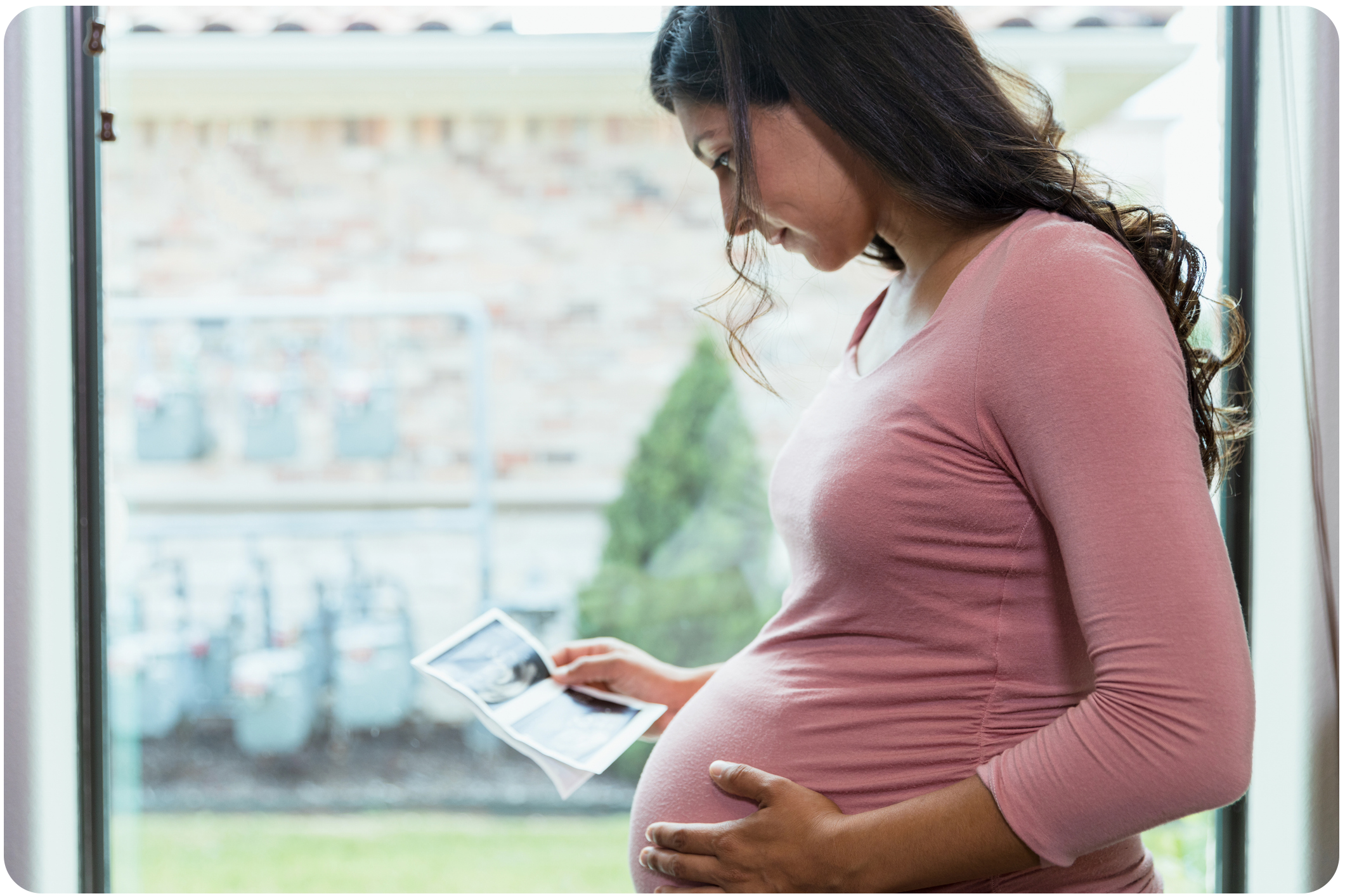 Pregnant woman in pink shirt viewing an ultrasound picture